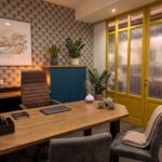 Salle de consultation d'un cabinet médical et paramédical à louer Bordeaux : bureau en bois, fauteuil et cloison vitrée jaune